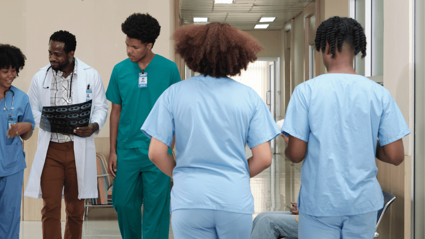 A team of healthcare professionals in scrubs walking through a hospital hallway.