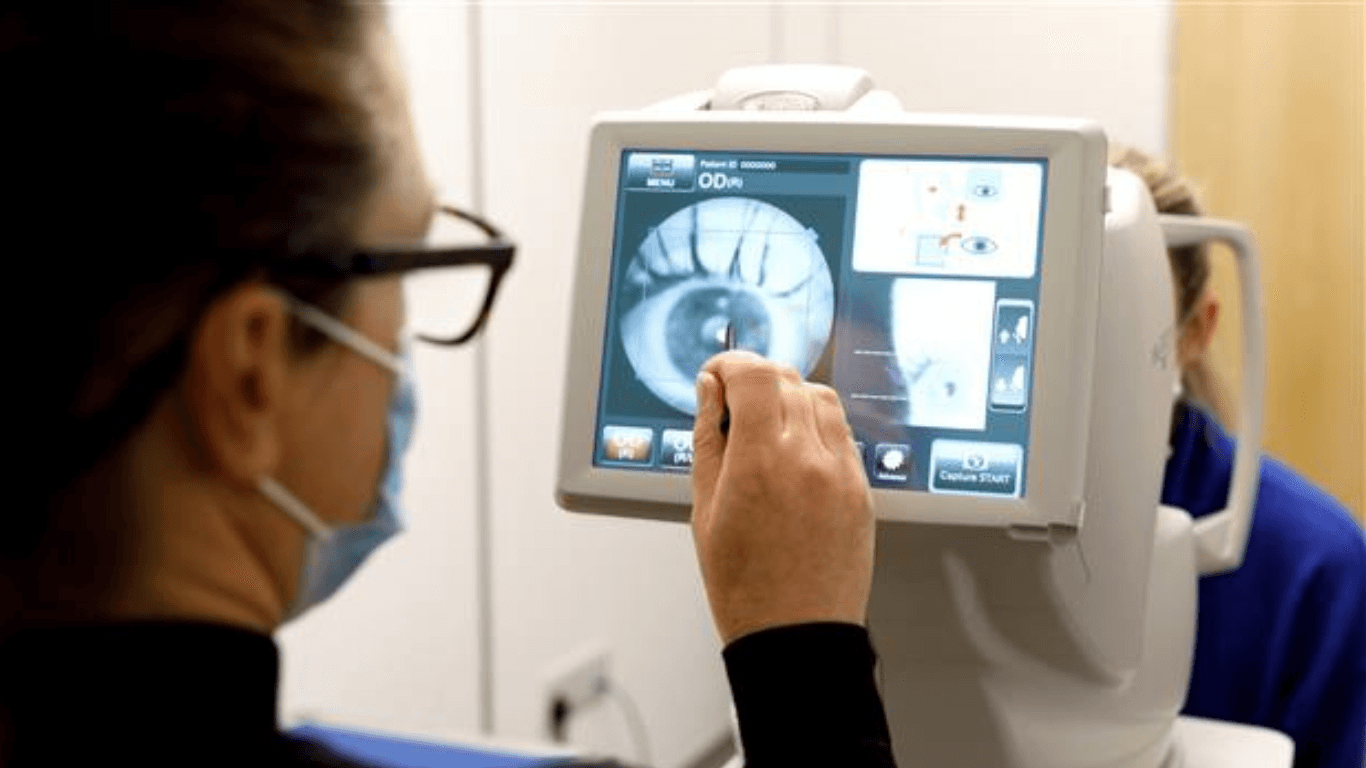 A woman examines an eye chart displayed on her computer screen for retinal screening