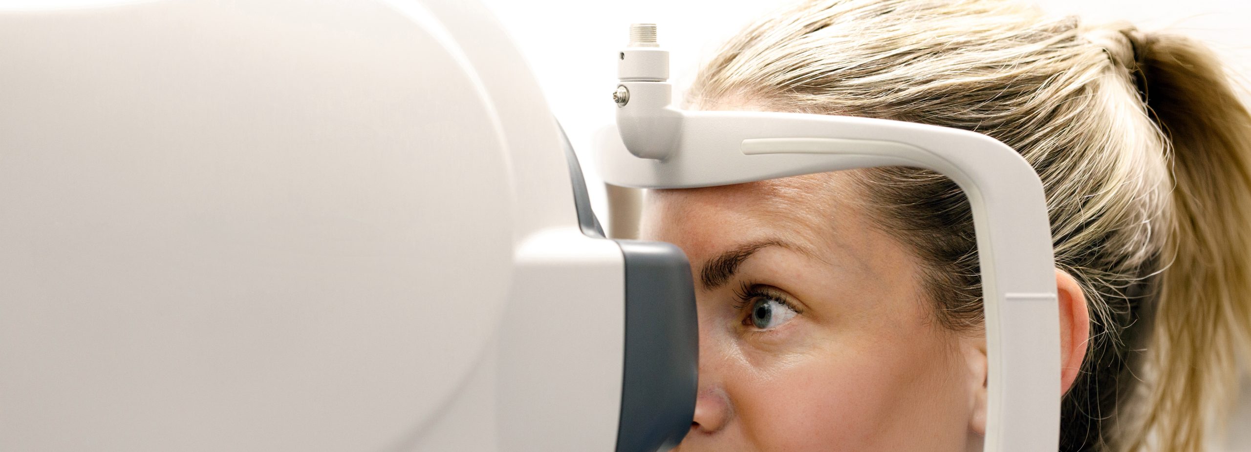 Close-up of a person undergoing an eye screening, looking into diagnostic equipment during a routine vision health exam.
